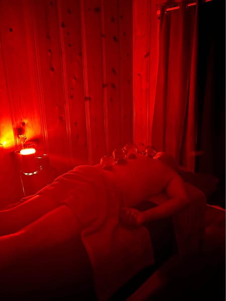 Aura Wellness - Professional therapeutic massage room with red therapeutic lighting